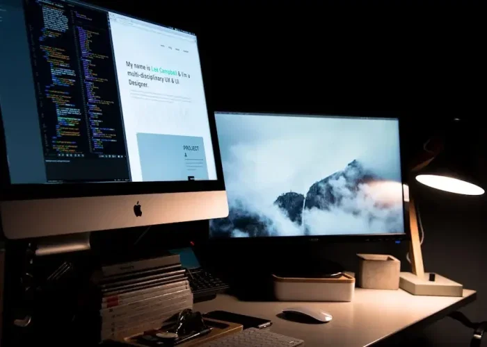 Webdesigner werkt aan een website op een laptop met kleurrijke schermen op de achtergrond